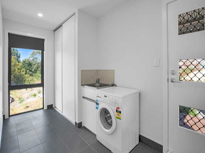 Spacious Laundry with Large Built-In Cupboard and Floor Level Window